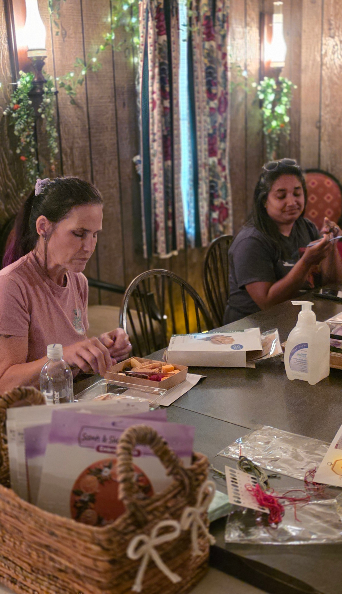 Two guests at a wooden table with craft kits and snacks