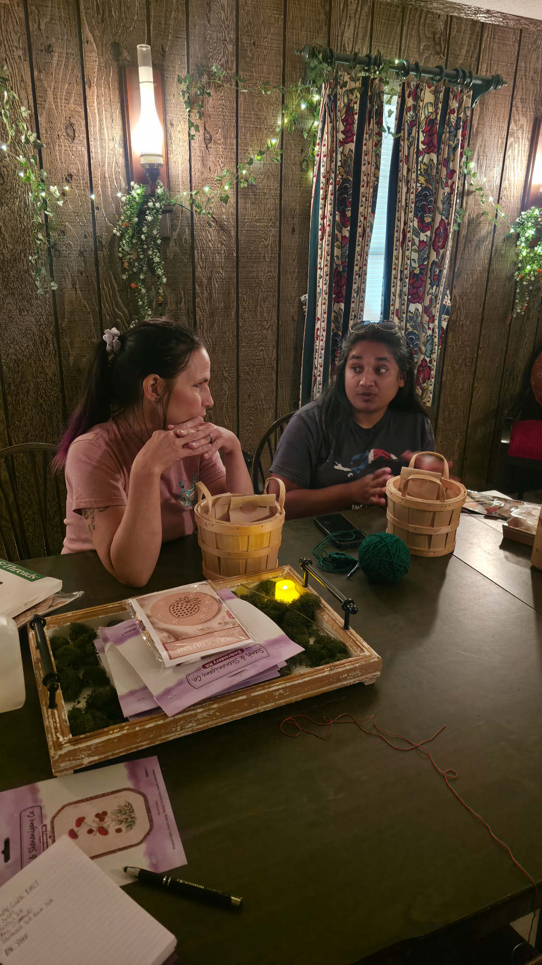 Two guests talking at a table with yarn and embroidery kits