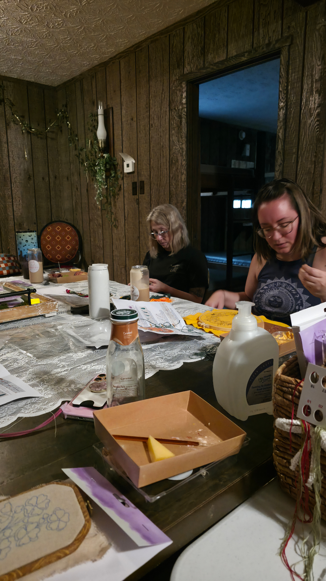 Two guests crafting at a table with a lacy tablecloth