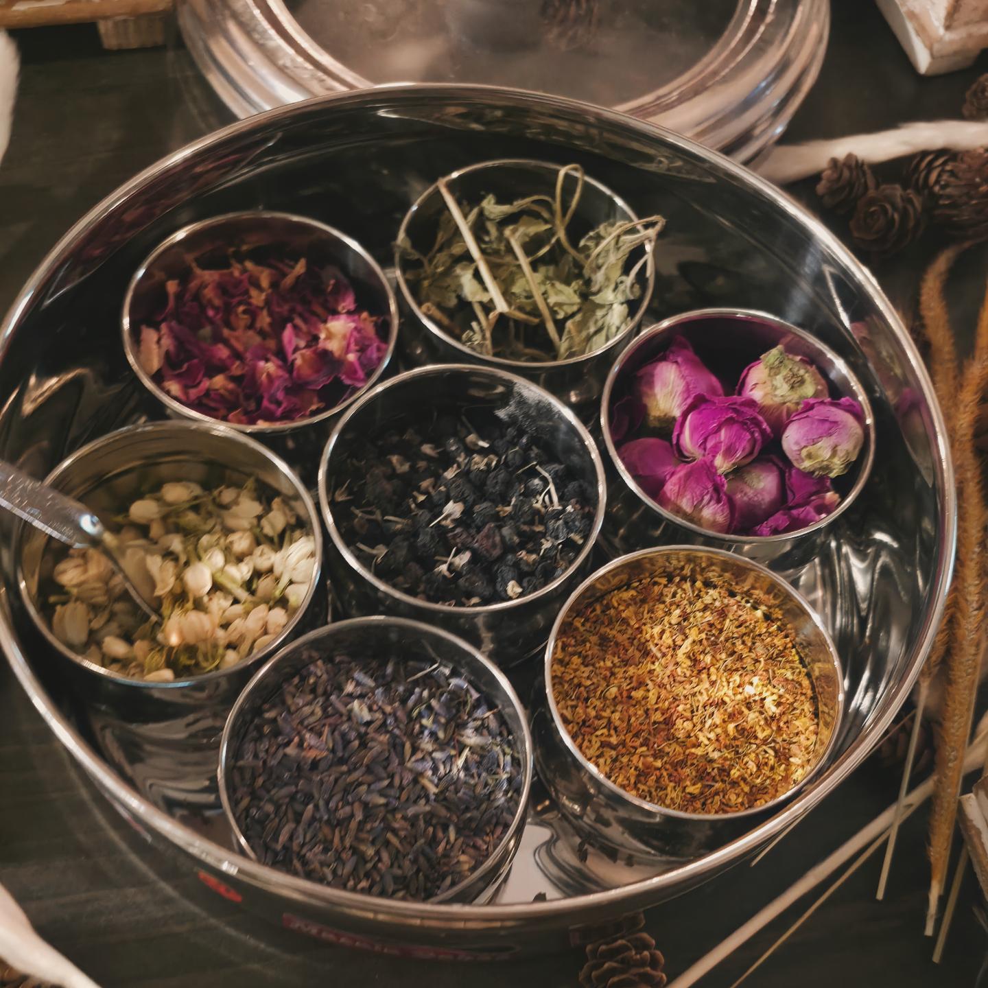 Tin of dried botanicals including rose petals, lavender, and jasmine