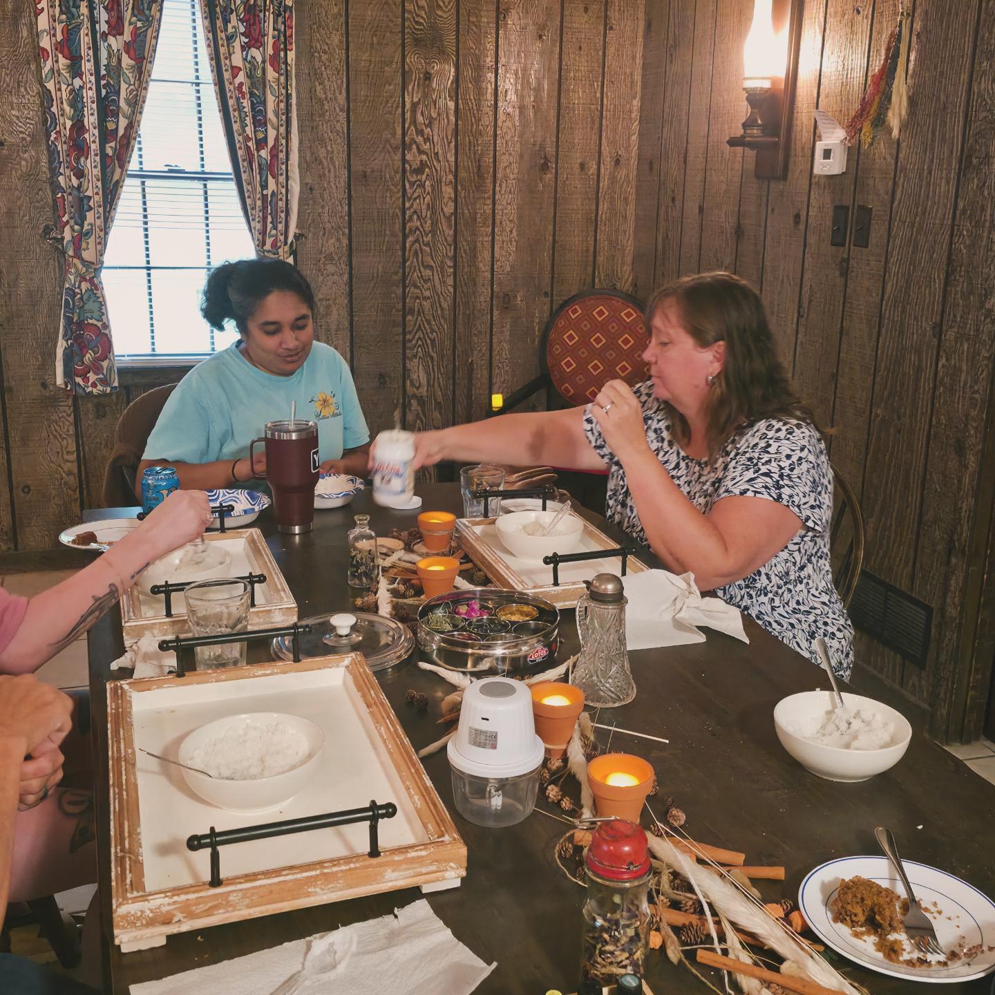 Guests mixing scrubs together at a candlelit wooden table